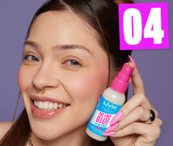 A smiling person holds a bottle of NYX \'The Brow Glue\' against a purple background, showcasing their long, manicured nails.